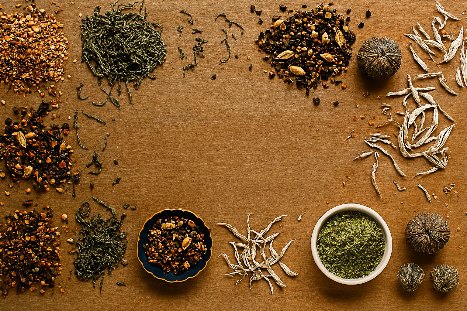 Plusieurs thés sur une table en bois : matcha, thé en vrac, thé aux boules de fleurs.